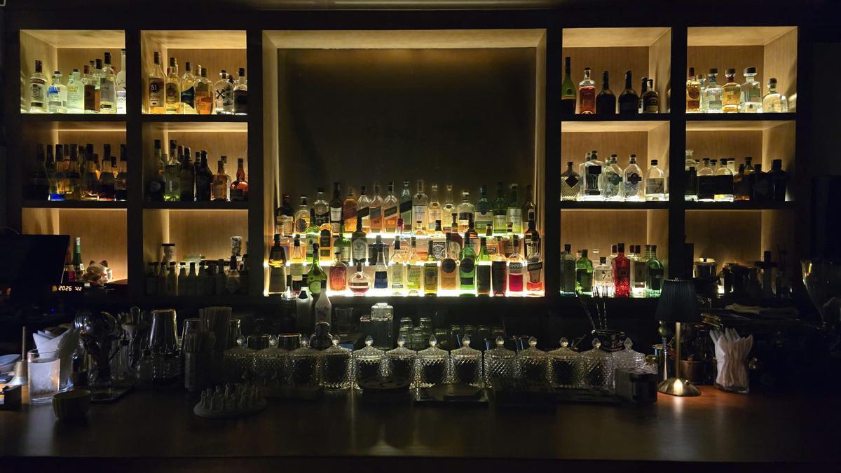 The full back bar at The 6ix Saigon, shelves of whisky, gin and tequila lit from behind