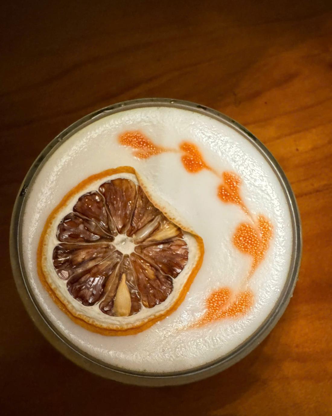 Sour cocktail with dried orange and bitters art on the foam