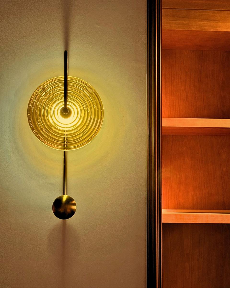 Brass and amber glass wall lamp beside the wooden shelves