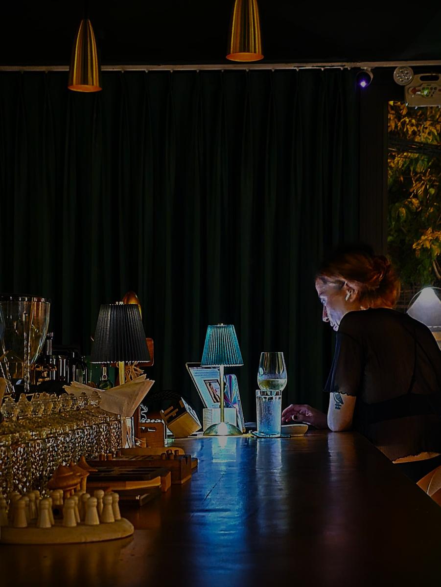 A guest at the bar under green velvet curtains and brass lamps