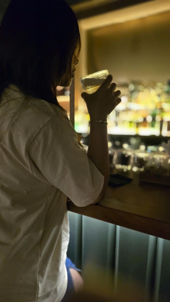 A guest sipping a cocktail at the bar counter